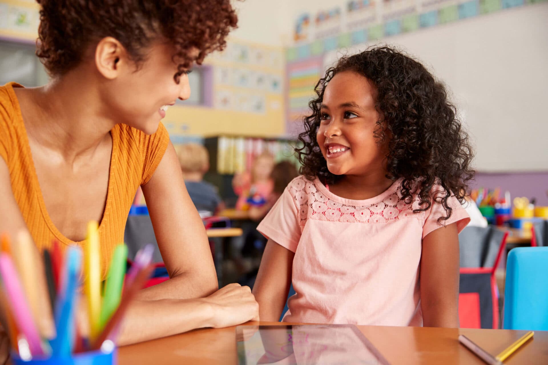 A teacher and a child smiling at each other in a The Village Learning Center classroom