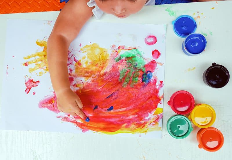 A young child finger-painting at The Village Learning Center