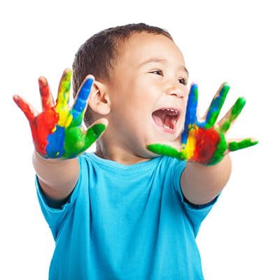 A happy toddler with painted hands at The Village Learning Center